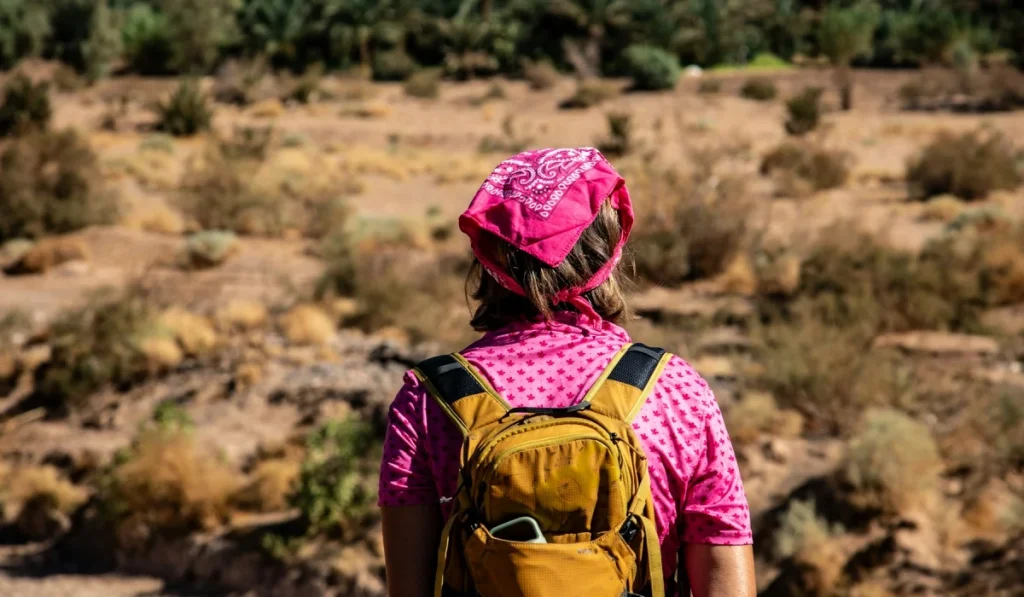 A traveller carrying a backpack while looking across an arid Moroccan landscape